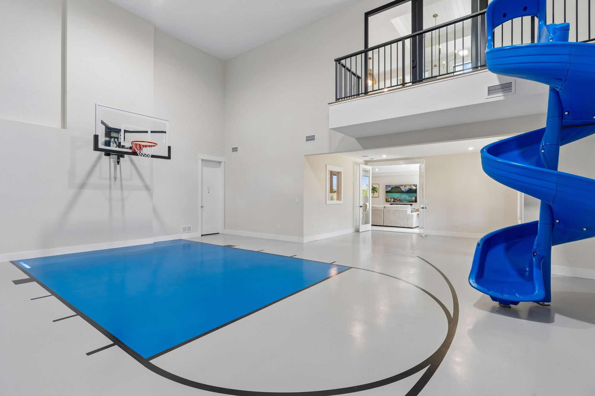 Indoor basketball court with upper viewing area and blue spiral slide